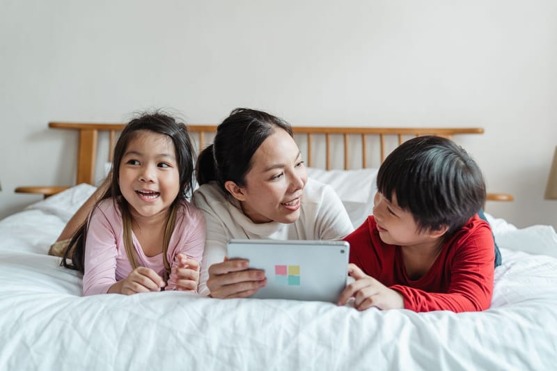 Eine Mutter lernt gemeinsam mit zwei Kindern an einem Tablet.